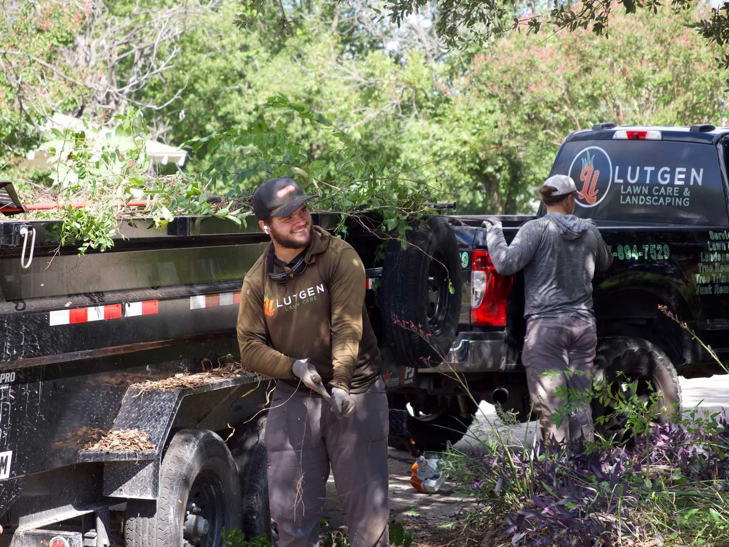 Lutgen Landscaping crew members working beside a branded truck on a Granbury property