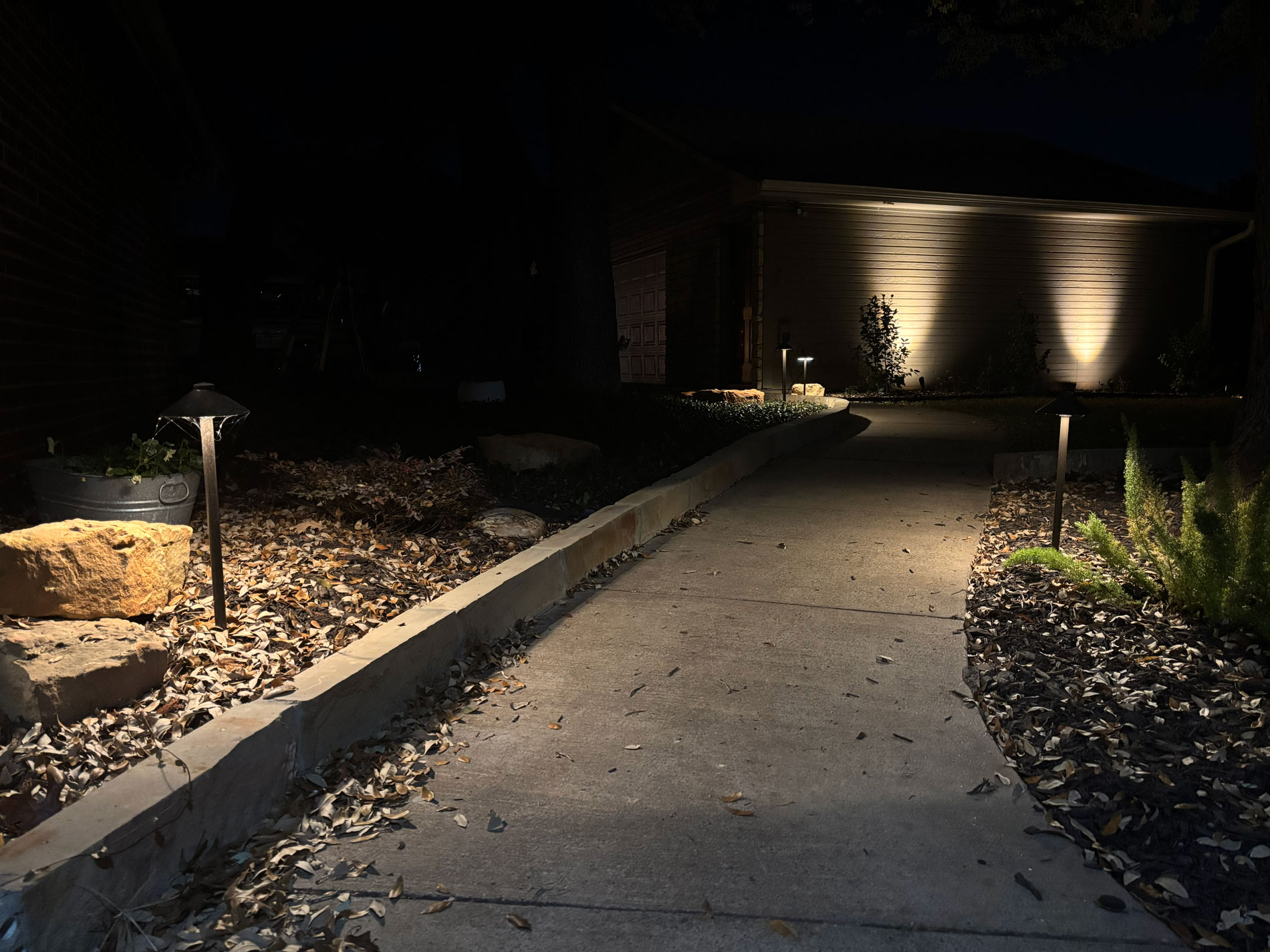 Warm architectural and pathway lighting across a finished property